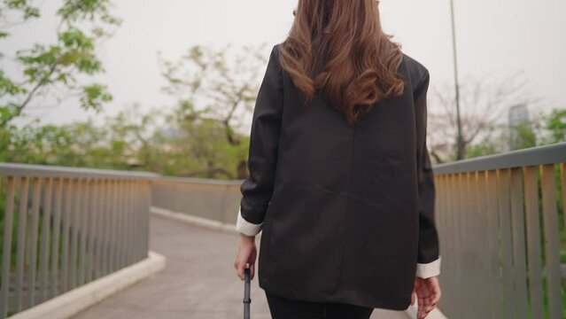 Shot from behind of businesswoman walking along the urban walkway afterwork, end of the day, formal suit walk home, job opportunity, independent elegance lady walking with pulse along city park walk