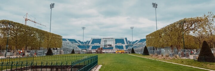 Empty sports stadium undergoing renovation with construction crane, signifying concepts of sports,...