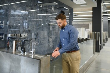 Playing with shower faucet. Man chooses a products in a sanitary ware store