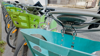 Row of colorful public rental bicycles with baskets in urban setting, concept of eco-friendly...