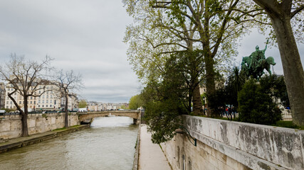 Serene view of the Seine River with greenery and equestrian statue in Paris, ideal for travel...