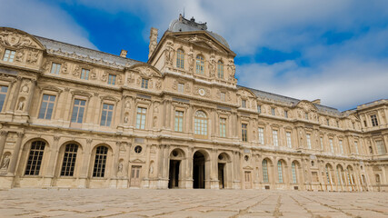 Fototapeta na wymiar Classical French architecture of the Louvre Museum under a blue sky, ideal for travel, tourism, and European heritage concepts