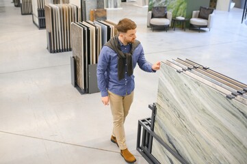 Young man choosing tiles at building market