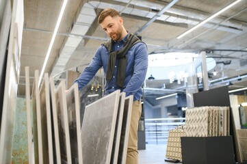 Young man choosing tiles at building market