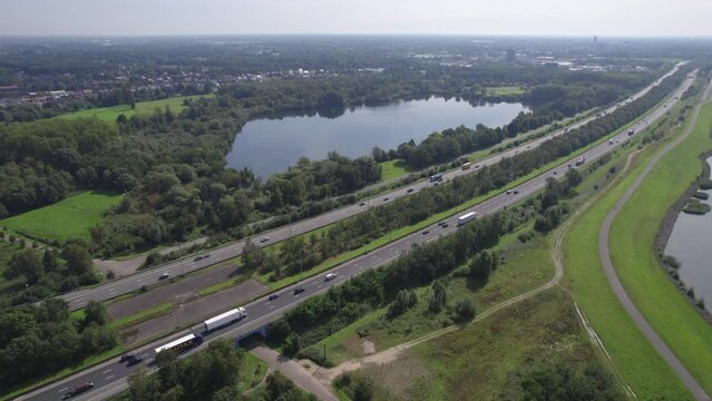 Captured from above Mechelen, this aerial slow-motion video offers a striking view of the E19 highway as it carves through the lush Belgian landscape, connecting Antwerp and Brussels. The calm waters