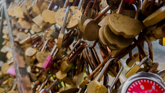 Assorted love padlocks attached to a bridge railing symbolizing eternal love and commitment, commonly seen in romantic Valentine's Day celebrations in Paris