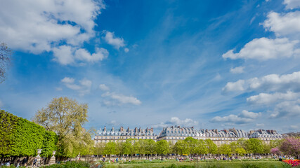 Spectacular view of Parisian architecture and public gardens under a vibrant blue sky with wispy...