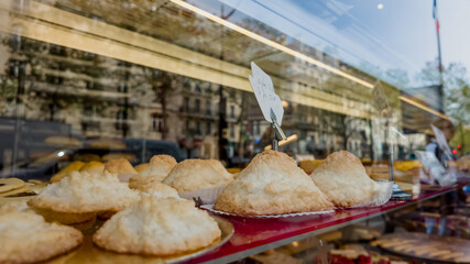 Golden-brown pastries on display with price tag in a bakery showcase, reflecting an urban street...