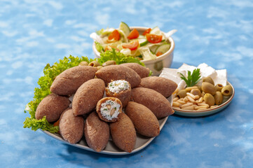 fried Arabic Lamb feta cheese Kibba with salad on a blue background