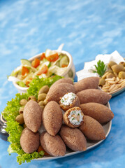 fried Arabic Lamb feta cheese Kibba with salad on a blue background
