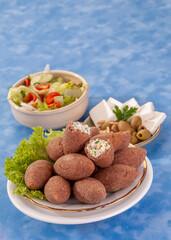 fried Arabic Lamb feta cheese Kibba with salad on a blue background