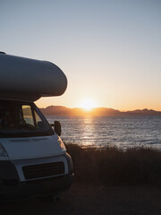 Motor home parked by the sea at beautiful sunset