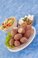 fried Arabic Lamb feta cheese Kibba with salad on a blue background