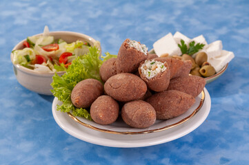 fried Arabic Lamb feta cheese Kibba with salad on a blue background