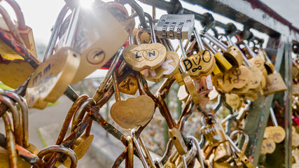 Sunlit love locks on a bridge railing symbolizing romance and commitment, ideal for themes like...