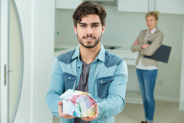 young man holding model house made from euro banknotes