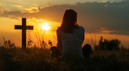 Devout faithful christian prays in front of the cross at a dramatic sunset with beautiful skies