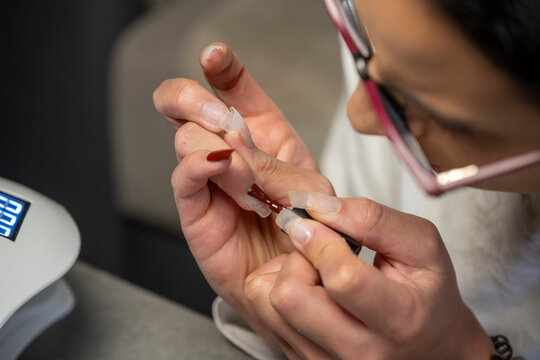 Jeune femme se faisant un manucure avec des capsules