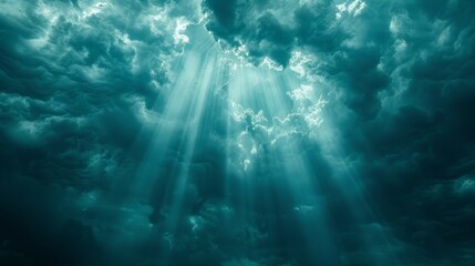 Obraz premium The sun shines through clouds in a dark blue sky, casting rays from cloud tops