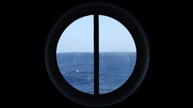 Boat POV of wavy seascape against clear sky seen through circular window