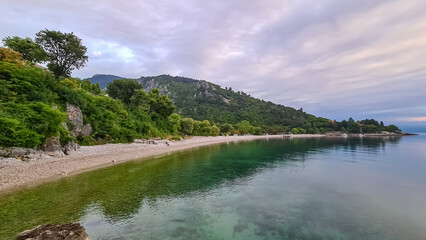 A stony beach along the shore of Medveja in Croatia. The Mediterranean Sea is calm and clear. There...
