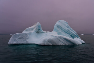 Solitary iceberg with purple skies, aqua water Greenland