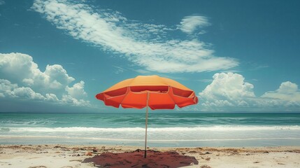 an orange umbrella is on the beach near the ocean
