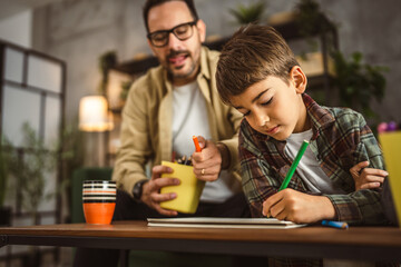 Father and son draw and paint together at home leisure activity