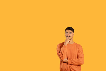 Man in Orange Shirt Standing With Hand on Chin