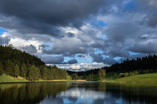 Lake Zlatna and green forest with clouds in background, Kezmarok, Slovakia. Sunny spring day.
