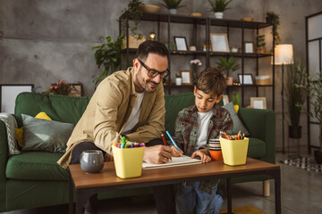 Father and son draw and paint together at home leisure activity