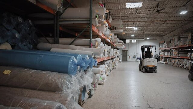 Piles of new rolls of carpet in a store warehouse. Carpet rolls stacked at store. Wide shot
