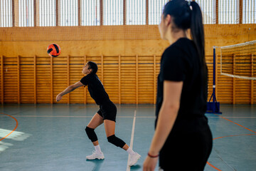 Naklejka premium Diverse female volleyball players practicing volleyball at indoor court
