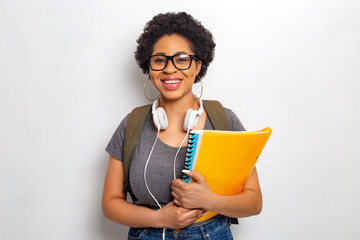 Portrait of a female student. A young African woman in glasses holds textbooks in her hands and smiles looking at the camera. The concept of education and training.