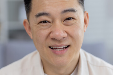 Fototapeta premium A high-resolution image featuring a close-up portrait of a cheerful middle-aged Asian man. His warm smile and confident eyes convey positivity and approachability.