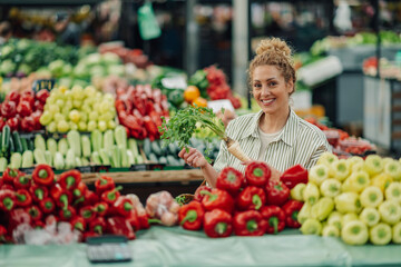 Fototapeta na wymiar Portrait of happy customer holding fresh produce at market and smiling