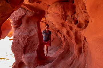 Woman standing in the fire cave and Windstone Arch in Valley of Fire State Park, Nevada, USA. Long,...