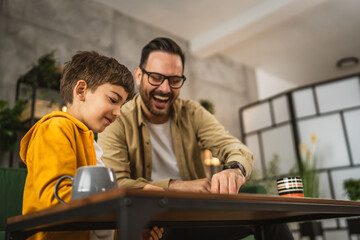 Father and son play board game together at home