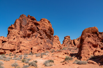 Fototapeta premium Exterior view of windstone arch and fire cave in Valley of Fire State Park, Mojave desert, Nevada, USA. Scenic view of beehive shaped red sandstone rock formations. Barren deserted landscape in summer