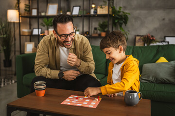 Father and son play board game together at home