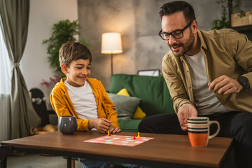Father and son play board game together at home