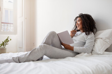 Woman Sitting on a Bed Reading a Book