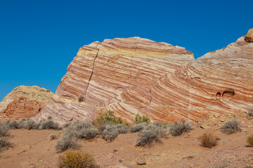 Scenic view of layered wavy red and white rock formations along the White Domes Hiking Trail in Valley of Fire State Park in Mojave desert, Nevada, USA. Unique natural landmark shaped like a wave