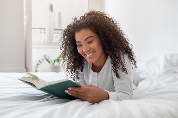 Positive Young Woman Reading Book on Bed