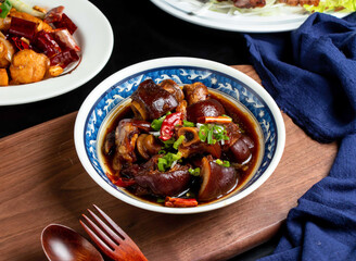 Braised pig feet with spring onion, red pepper, spoon and fork served in dish isolated on wooden board side view of taiwan food