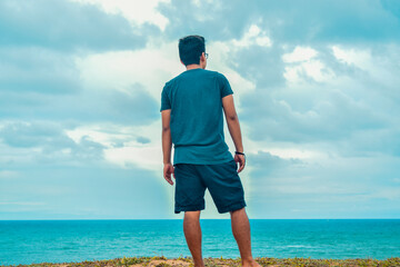 man meditating on the shore of a beach, looking at the horizon

