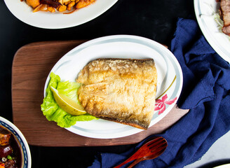 Pan fried fish maw with lemon, spoon and fork served in dish isolated on wooden board top view of taiwan food