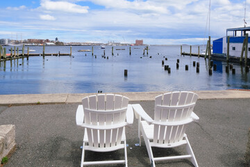 couple of wooden empty chairs on the pier at bay waterfront, vacation memories, calm down