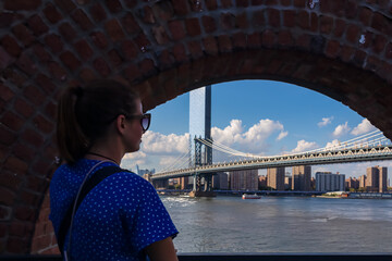A woman in sunglasses enjoying the view on iconic Manhattan Bridge connecting New York City's urban landscape with stunning skyline. Tall skyscrapers. Famous spot for sightseeing. Chilling and relax