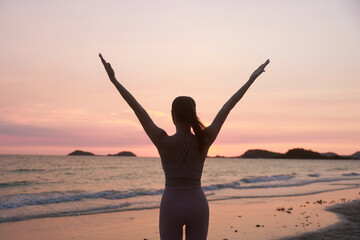 Fototapeta premium Silhouette workout woman stretching arms and legs exercising during sunset at the beach, Yoga concept